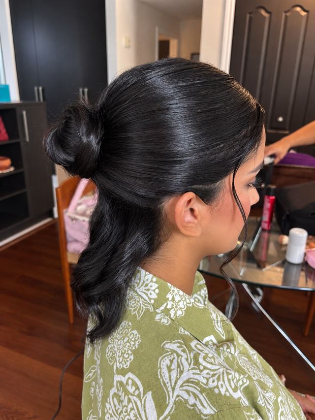 Sleek dark half-up style with a low knot and soft waves