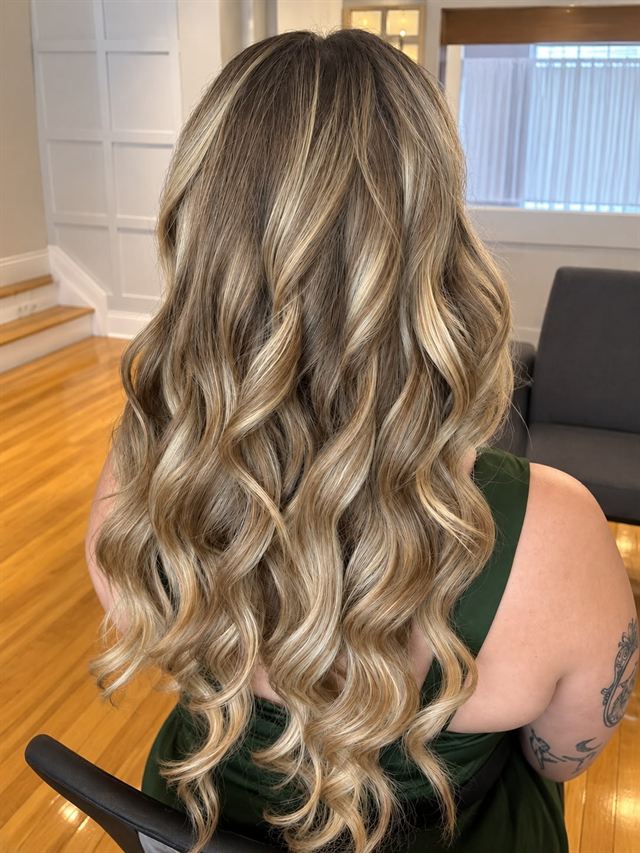 Long blonde balayage in defined curls, seen from behind