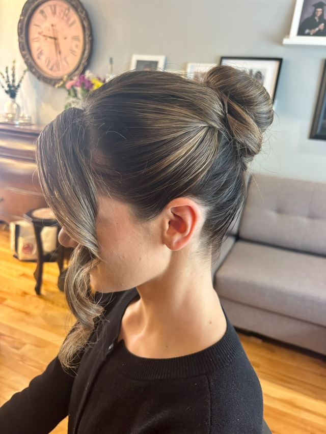 High bun on balayage hair with a long face-framing curl