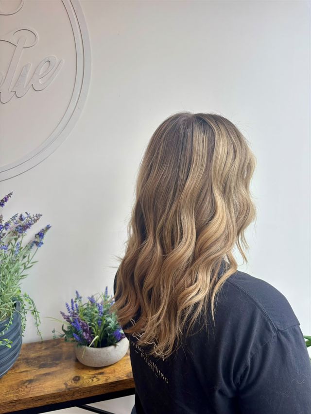 Sandy blonde balayage in soft waves, side view